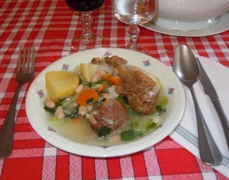 Assiette de garbure au confit de canard sur une nappe à carreaux, au restaurant